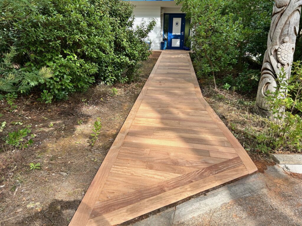 Chemin stabilisé en gravier longeant la façade d'une maison, avec bordure nette et bande drainante au pied du mur